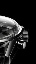 Close-up of a luxury men's wristwatch with polished metal case and textured crown